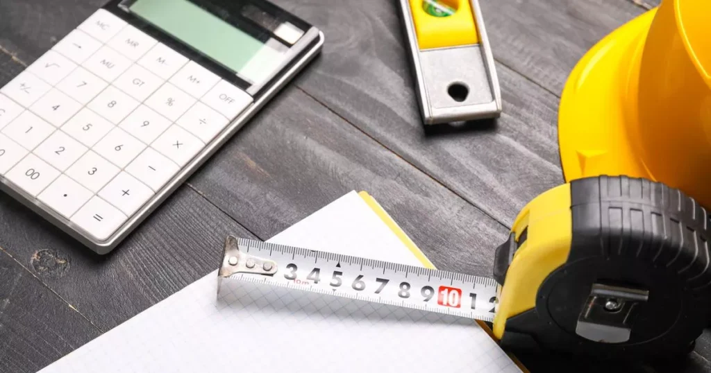 Measuring tape with builder's supplies, calculator and notebook