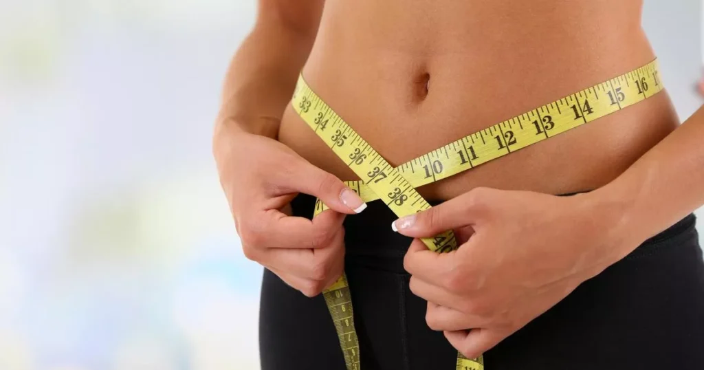 Woman measuring her waist with tape